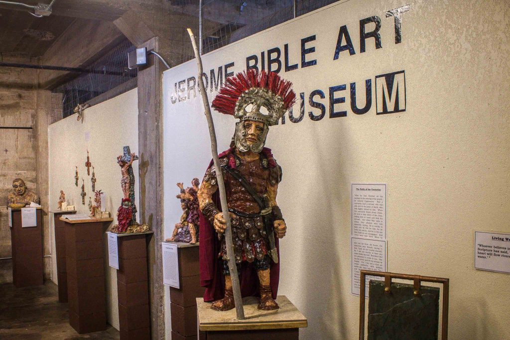 Gladiator figurines on pedestals in front of a wall reading “Jerome Bible Art Museum.”