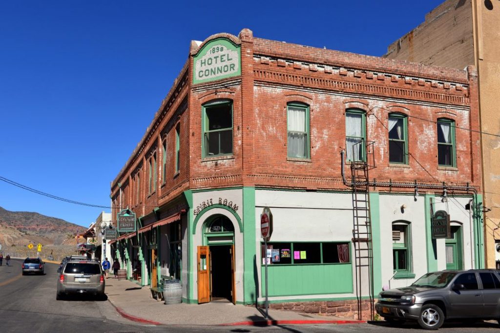 Two-story brick building with green trim and a sign reading "1898 Hotel Connor."