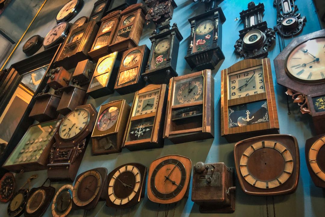 Varying styles of vintage clocks on a blue wall.
