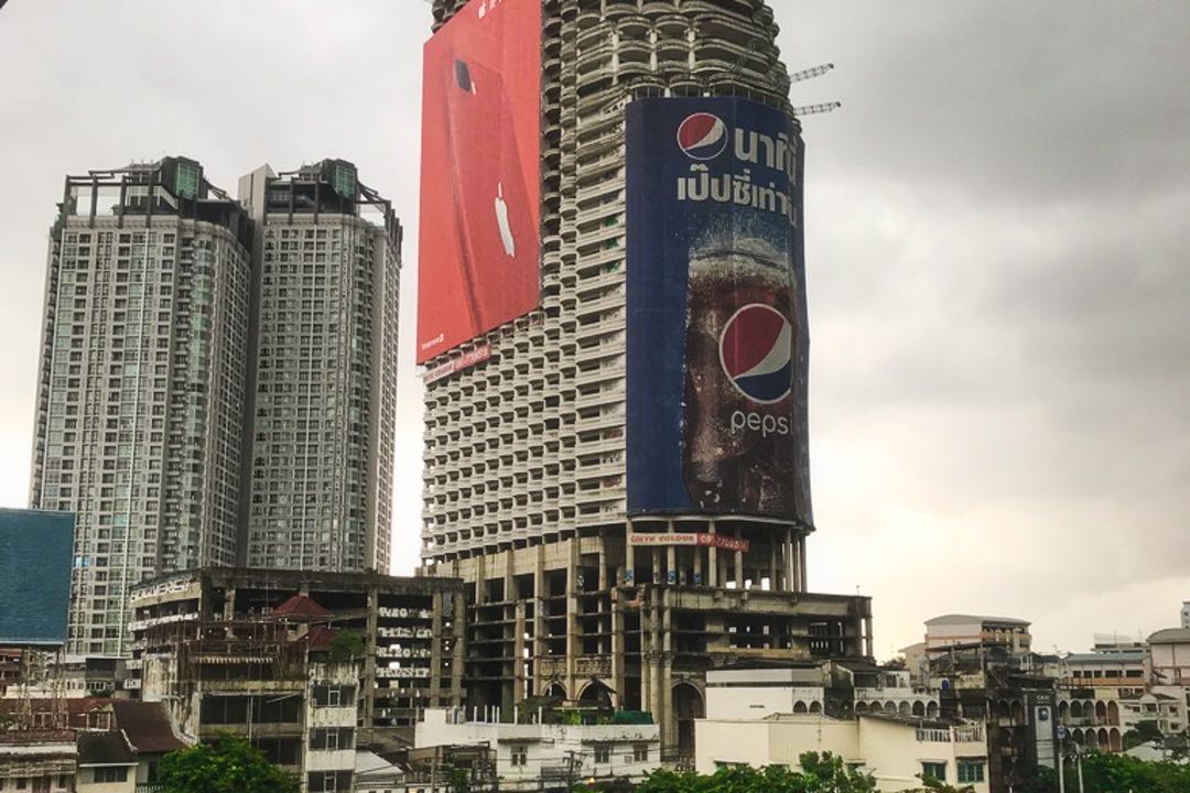 Unfinished skyscraper covered with large Pepsi banner and seen from a distance.