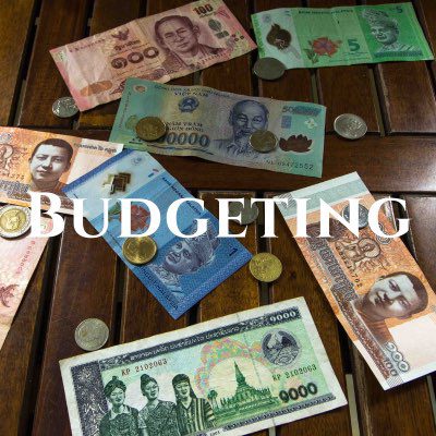 "Budgeting" written across a photo of coloring Thai baht and coins spread out on a wooden table.