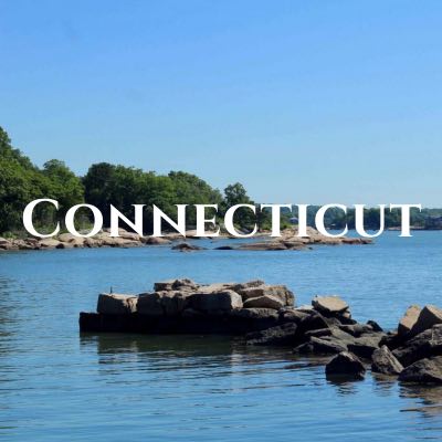 "Connecticut" written across a photo of a strip of rocks jutting into the water in front of a tree-lined shore.