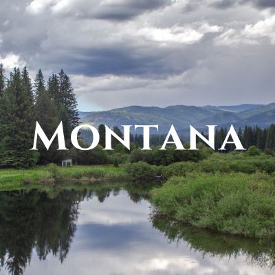 "Montana" written across a photo of hills and pine trees above their reflection in water.