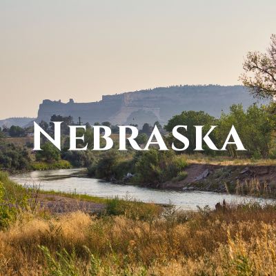 "Nebraska" written across a photo of a winding river in drove of a large rock formation.