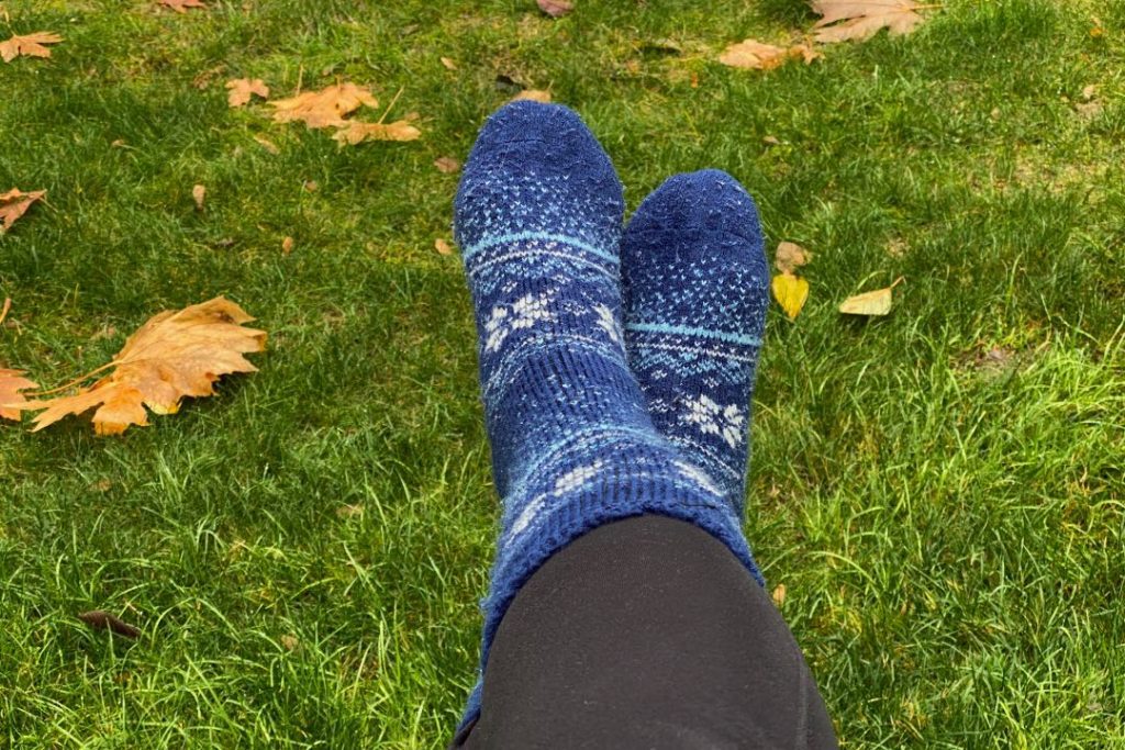 Two feet wearing tall navy and white socks, stretched out in the grass.