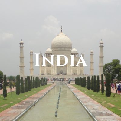 "India" written across a photo looking down a reflecting pool to the Taj Mahal, with symmetrical paths, trees, and stone columns on both sides.