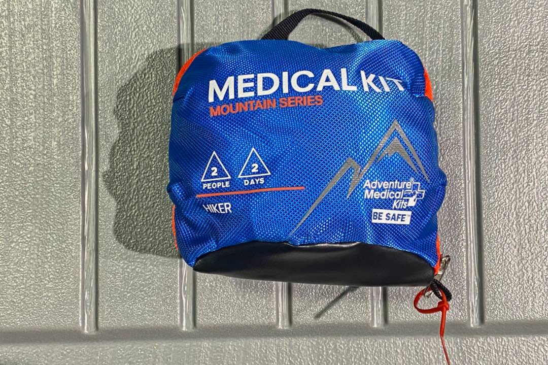 Blue zippered pouch reading "Medical Kit Mountain Series," "2 People 2 Days Hiker," and "Adventure Medical Kits Be Safe."