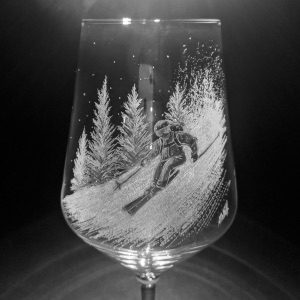 Wine glass engraved with a downhill skier in front of pine trees.